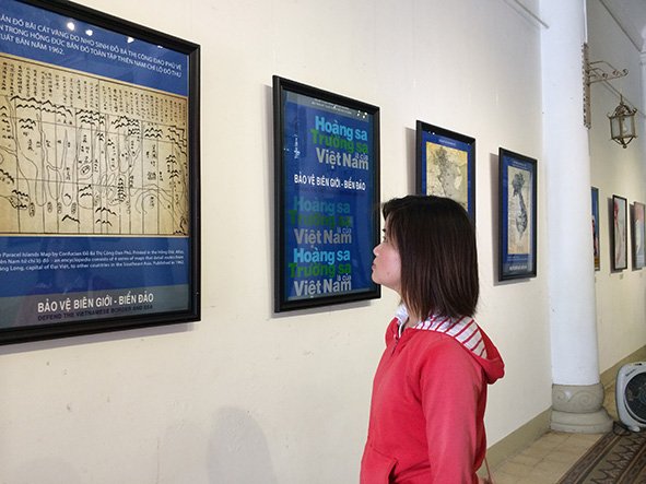 A visitor inspects works on display at the exhibition ‘Defend the Vietnamese border and sea’ at HCMC Fine Arts Museum