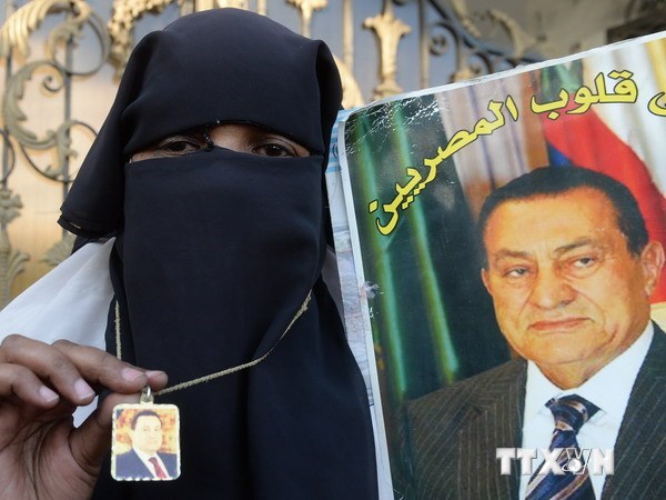 Một người ủng hộ cựu Tổng thống Hosni Mubarak cầm ảnh của ông bên ngoài bệnh viện nơi ông điều trị ở Cairo. (Nguồn: AFP/TTXVN)