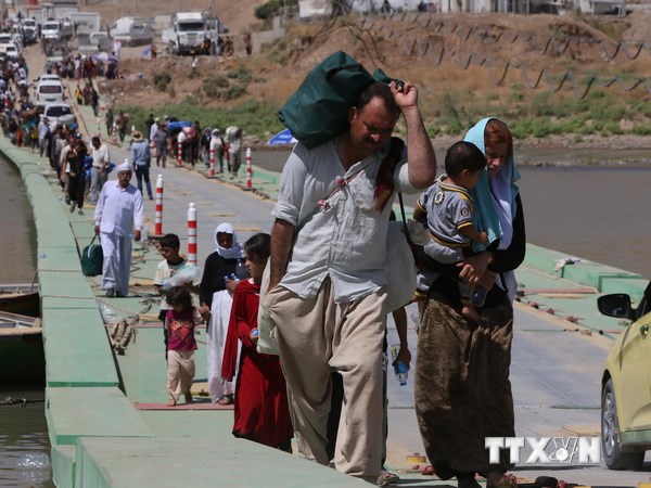 Cộng đồng người Yazidi trở về Iraq khi đi dọc biên giới trên cây cầu Fishkhabur bắc qua sông Tigris, qua cửa khẩu Fishkhabur, miền bắc Iraq ngày 11/8. (Nguồn: AFP/TTXVN)