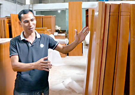 Anh Nguyễn Công Vinh đang giới thiệu về sản phẩm nội thất được thiết kế từ gỗ xoan đào.