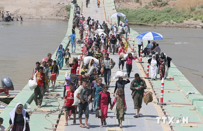 Cộng đồng người Yazidi trở về Iraq khi đi dọc biên giới trên cây cầu Fishkhabur bắc qua sông Tigris, qua cửa khẩu Fishkhabur, miền bắc Iraq ngày 11/8. (Ảnh: AFP/TTXVN)