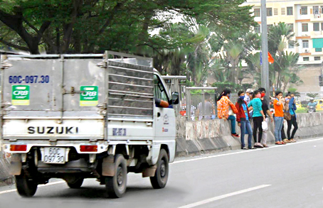 Thay vì đi lối cầu bộ hành, nhiều người qua đường bằng cách leo dải phân cách. Ảnh: N. LIÊN