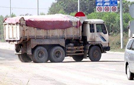 Xe tải ben phủ bạt lòi đất, đá lưu thông ra đường Võ Nguyên Giáp gây rơi vãi, làm ô nhiễm, mất an toàn giao thông trên đường.