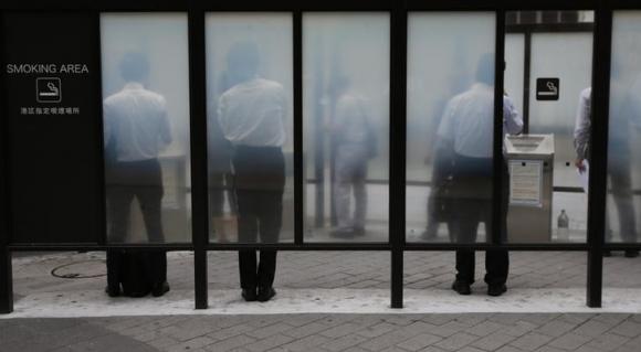 People smoke cigarettes at a smoking booth on a street in Tokyo August 25, 2014.