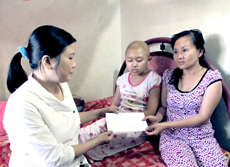 Đại diện Báo Đồng Nai (trái) trao tiền ủng hộ cho gia đình em Võ Trần Hồng Thắm. Ảnh: Kim Liễu