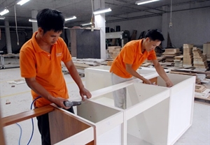 Workers make furniture at the Ha Noi-based Ha Lam Import Export Co. Export of wooden products is expected to continue growing by at least 15 per cent this year.