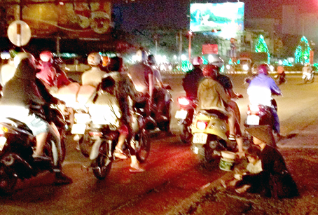 Một phụ nữ cùng đứa trẻ đang xin ăn tại ngã tư trước cổng Thư viện tỉnh. ảnh: Kim Liễu