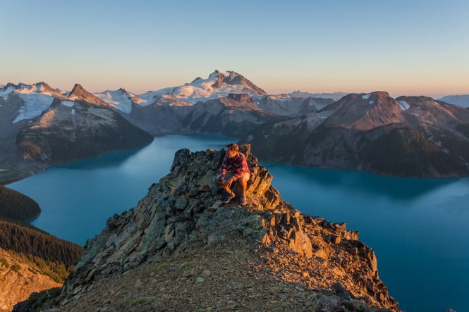  A man sits at Panorama Ridge in Canada during a sunset.