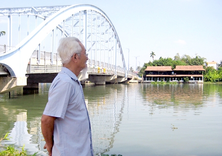 Ông Võ Văn Tư bên dòng sông đã gắn bó thời thơ ấu của mình, bên cạnh là cầu Hiệp Hòa.