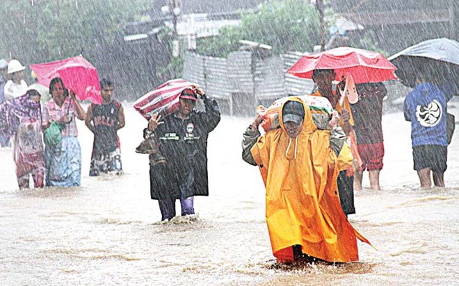 Người dân đi trong cơn mưa do bão Egay gây ra. (Nguồn: mb.com.ph)