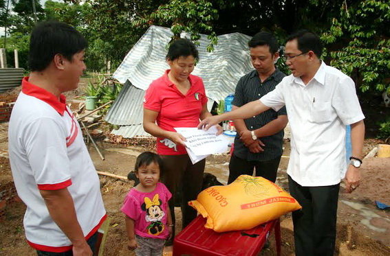 Ông Trần Đăng Ninh, Giám đốc Trung tâm Văn miếu Trấn Biên (ngoài cùng bên phải) trao tặng các phần quà do ông vận động được cho gia đình bà Nguyệt.