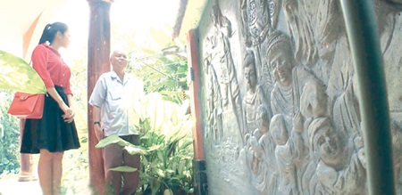 Memorial: Retiree Pham Van Khoat (right) introduces a mural relief depicting The Tale of Kieu to a visitor at his house in the southern province of Dong Nai. Khoat loves Nguyen Du's epic so much that he built a garden based on the story covering 3,000sq.m.