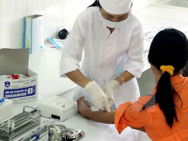 Cán bộ y tế của Trung tâm phòng chống HIV/AIDS tỉnh Ninh Bình lấy mẫu máu xét nghiệm HIV/AIDS cho khách hàng. (Ảnh: Dương Ngọc/TTXVN)