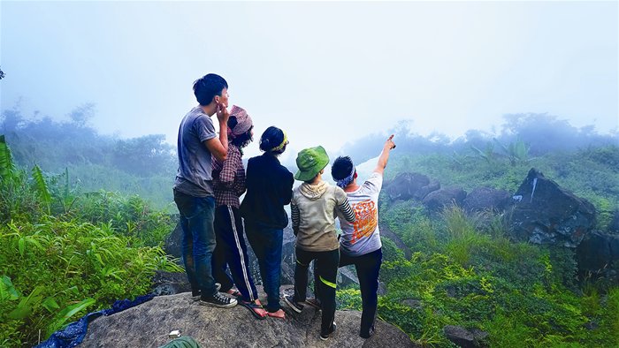 People are seen climbing large rocks, the first challenge to get to Ba Den Mountain summit .