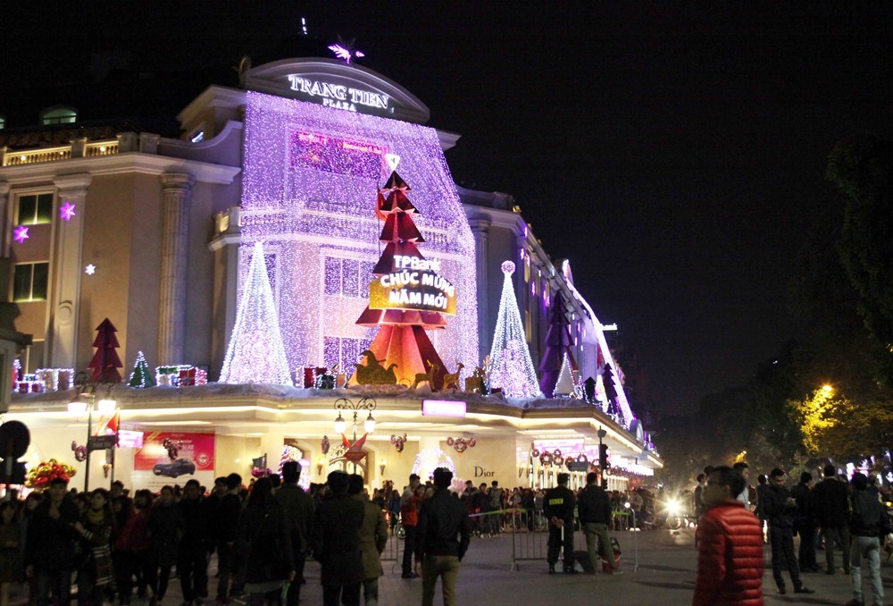 People walk in front of illuminated Trang Tien Plaza in Hanoi ​in the evening of December 31