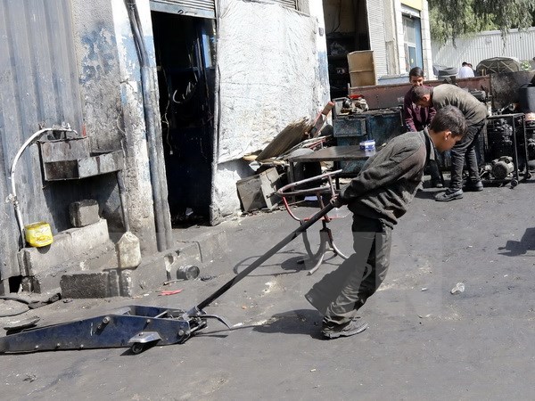 Một cậu bé Syria 12 tuổi phải làm các công việc nặng nhọc để kiếm sống tại một xưởng cơ khí ở thủ đô Damascus ngày 10/3. (Nguồn: AFP/TTXVN)