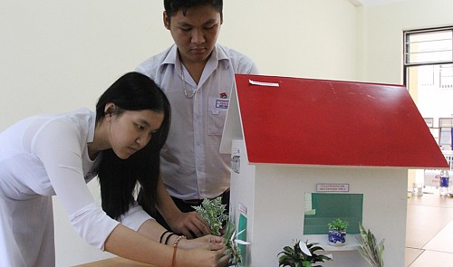 Tran My Duyen (L) and Quach Duc Huy are pictured making small changes to their house model.