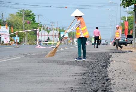 Công nhân đang vệ sinh phần đường sau khi phần trồi lún được cào bóc đi.