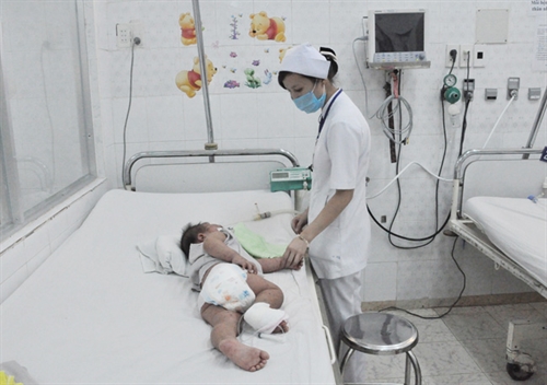 A medical worker takes care of a child suffering from foot-hand-mouth disease in the southern province of Đồng Nai. – Photo suckhoedongnai.vn  Read more at http://vietnamnews.vn/society/298947/foot-hand-mouth-disease-cases-rise-in-dong-nai.html#jtk5VEhXCvlsyqjb.99