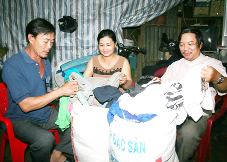 Ông Nguyễn Văn Bình, Chủ tịch Hội Chữ thập đỏ xã Trung Hòa (bìa phải) và ông Hà Hữu Hiếu, Đội trưởng Đội công tác xã hội thuộc Hội Chữ thập đỏ xã, đang sắp xếp lại những bộ quần áo cũ quyên góp được để chuẩn bị trao tặng cho người nghèo.