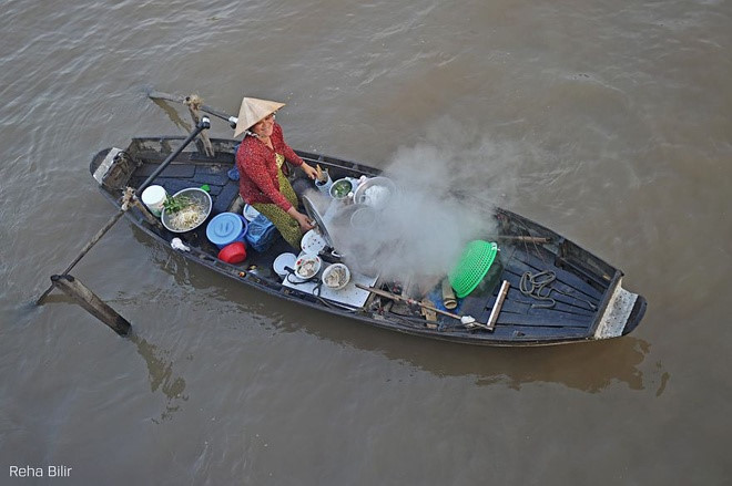 Woman selling food on Me Kong River by Reha Billr