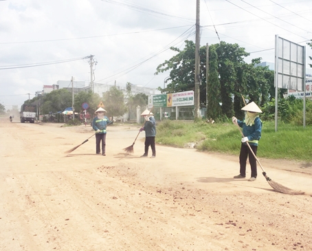 1. Công nhân vệ sinh đang dọn dẹp, hốt từng chút đất cát do xe tải làm rơi vãi vật liệu trên đường.