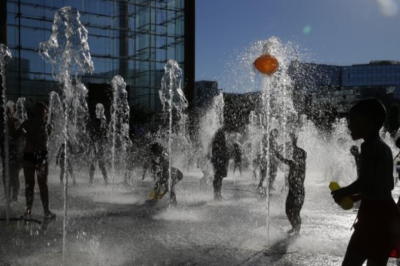 People are seen in silhouette as they cool off in water fountains in a park as hot summer temperatures hit Paris, France, August 24, 2016. 