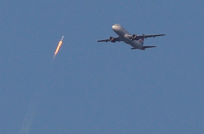 A recycled SpaceX Falcon 9 rocket soars toward space above a Virgin Airlines passenger jet, which had just departed Orlando International Airport, in Orlando, Florida, March 30, 2017. The launch marked the first time ever that a rocket was reused for spaceflight. REUTERS/Gregg Newton