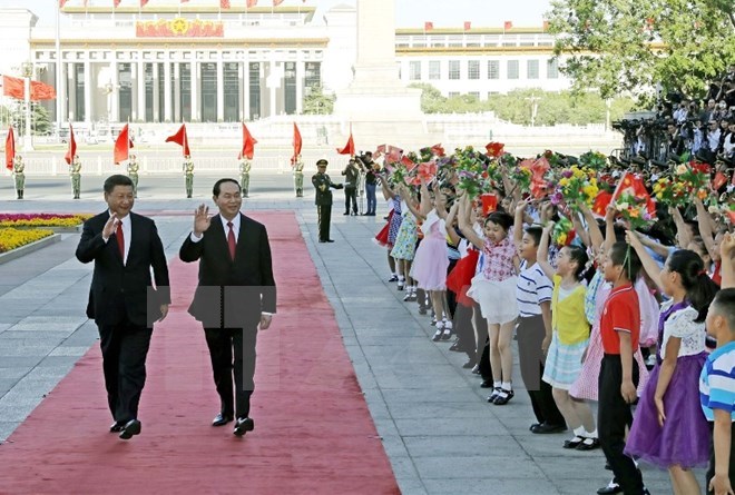 President Tran Dai Quang (R) and Party General Secretary and President of China Xi Jinping wave at children at the welcoming ceremony for the Vietnamese State leader