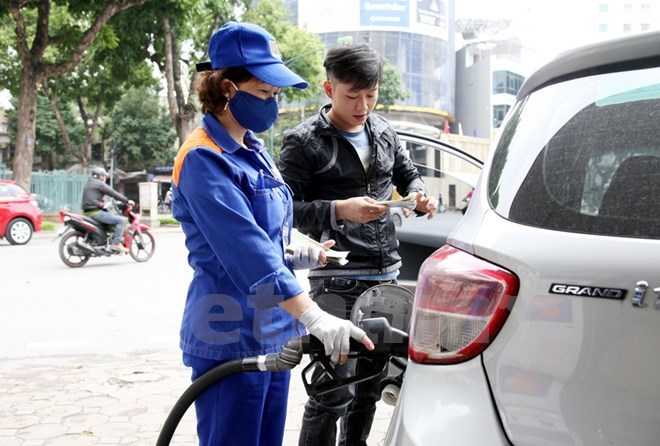 A staff sells fuel for a customer at a Petrolimex filling station (Photo: VNA)