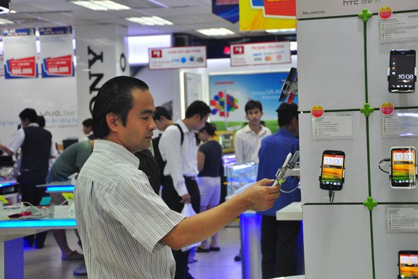 A customer inspects a phone at a Nguyen Kim shopping center - PHOTO: MINH TAM