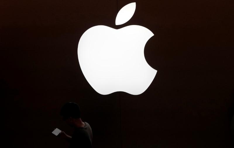 A man looks at the screen of his mobile phone in front of an Apple logo outside its store in Shanghai, China July 30, 2017.