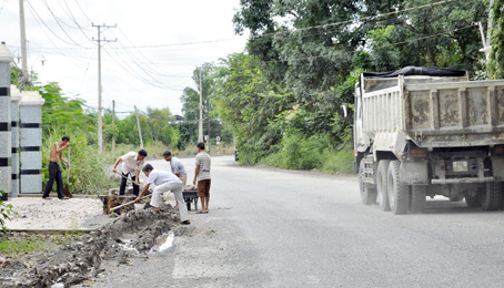 Người dân ấp Tân Cang thu dọn đất, đá, bùn sau thời gian dài xe tải ben hoạt động trên đường Đinh Quang Ân (ảnh chụp ngày 24-9).