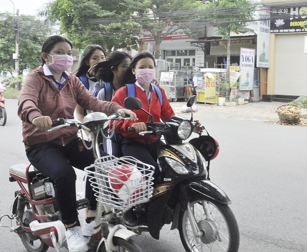 Học sinh chạy xe máy chở 3 đẩy một học sinh đi xe đạp điện (trên một tuyến đường ở phường Tân Hiệp, TP.Biên Hòa), tất cả đều không đội mũ bảo hiểm.