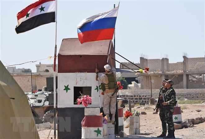 Cờ Syria (trái) và cờ Nga tại khu vực Abu Duhur, tỉnh Idlib ngày 25-9-2018. (Ảnh: AFP/TTXVN)