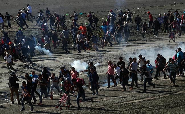 Người di cư vào Mỹ bỏ chạy trong làn khói cay. (Nguồn: NDTV)