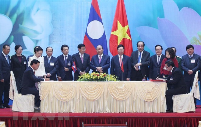 Vietnamese Prime Minister Nguyen Xuan Phuc and his Lao counterpart Thongloun Sisoulith witness the signing of cooperation agreements at the meeting 