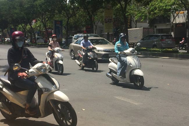 HCMC residents are seen traveling on Truong Son Street, Tan Binh District. Some provinces in southern Vietnam are experiencing heat waves, with daily temperatures reaching 35-38 degrees Celsius - PHOTO: THANH HA