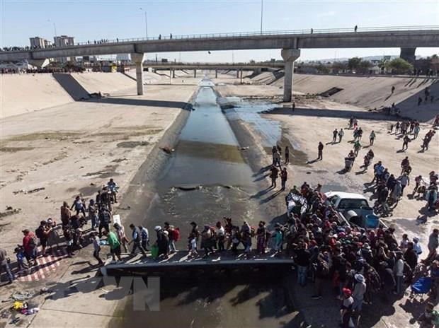 Người di cư Trung Mỹ vượt đoạn sông Tijuana để tới cửa khẩu El Chaparral, gần biên giới Mỹ-Mexico. (Ảnh: AFP/TTXVN)