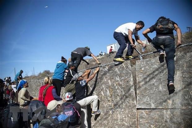 Người di cư Trung Mỹ vượt qua hàng rào biên giới Mỹ-Mexico ở Tijuana, bang Baja California, Mexico. (Nguồn: AFP/TTXVN)