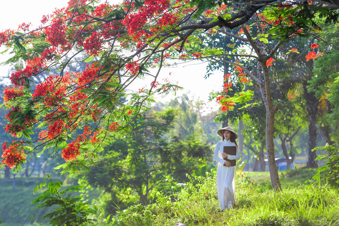 A girl wearing an Ao Dai poses for a scenic photo on the banks of the Huong river.