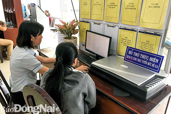Người dân được công chức Bộ phận tiếp nhận và trả kết quả của UBND TP.Long Khánh hướng dẫn các bước thực hiện nộp hồ sơ, đăng ký trực tuyến. Ảnh: Minh Thành