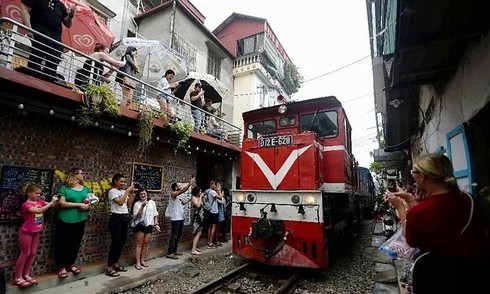 For some visitors there is a thrill in standing so close to a train as it rumbles through the old-style houses. Photo by AFP/Nhac Nguyen.