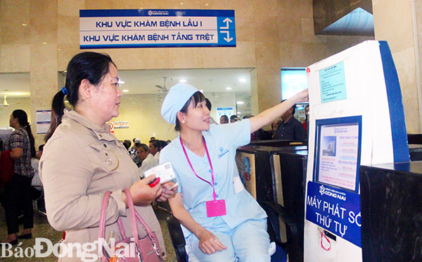 Người dân có thẻ bảo hiểm y tế được nhân viên Bệnh viện đa khoa Đồng Nai lấy số thứ tự tự động, hướng dẫn đến Khu Khám bệnh. Ảnh: H.Dung