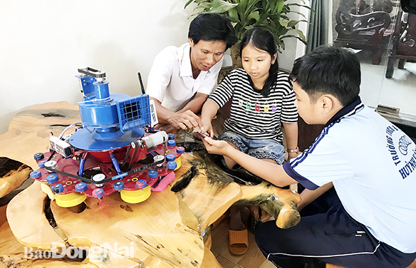 Anh Phạm Quang Khải hướng dẫn con gái Phạm Phương Vy và bạn là Mai Anh Dũng về nguyên tắc  vận hành của máy lau nhà, hút bụi tự động