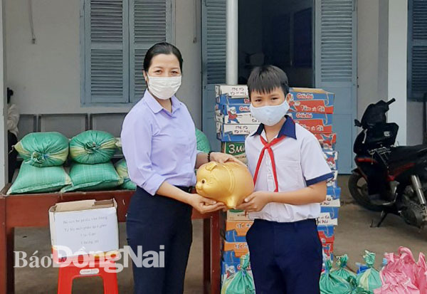 Em Hoàng Xuân Hải, lớp 5 Trường tiểu học Võ Thị Sáu (xã Sông Ray, H.Cẩm Mỹ) tặng heo đất tiết kiệm cho lãnh đạo xã