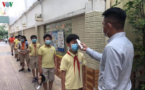 Pupils of a primary school in Ho Chi Minh City have their body temperature checked before entering the classroom