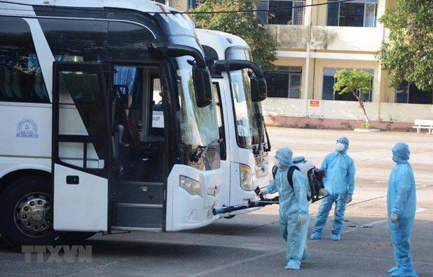 Medical workers spray disinfectant onto coaches carrying Vietnamese citizens brought home from the Republic of Korea (Source: VNA)