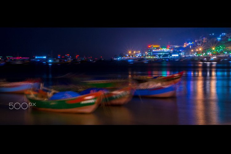 Colourful boats are seen anchored on the city's river at night 