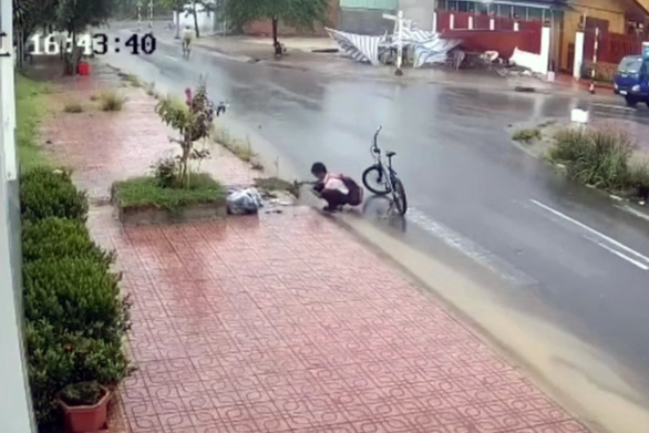 Phạm Trọng Đạt in the uniform of Long Thành Secondary School in Đồng Nai Province was seen to remove trash from a drain on June 16. — Image extracted from CCTV by tuoitre.vn